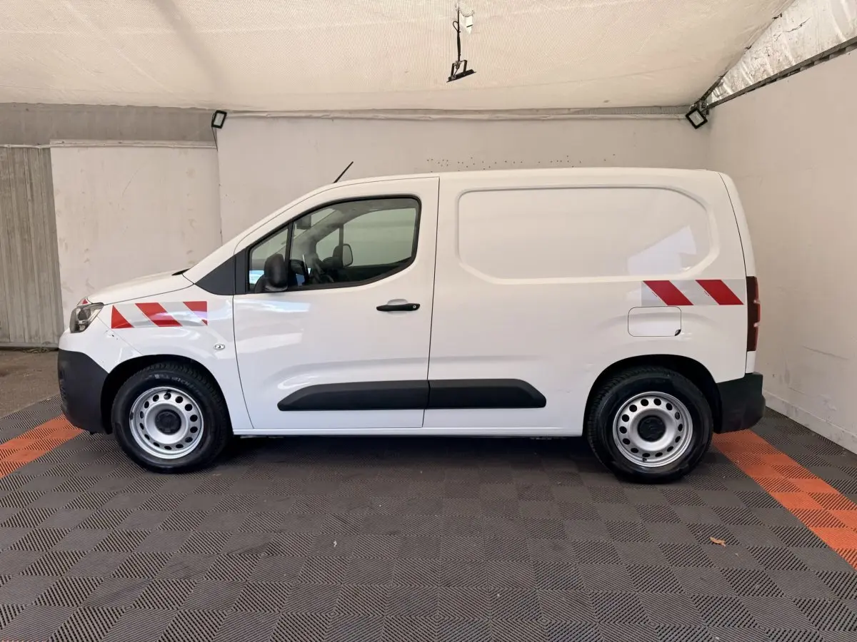 Vue de profil côté gauche d’un Citroën Berlingo blanc 2019 avec bandes réfléchissantes rouges sur les ailes avant et arrière.