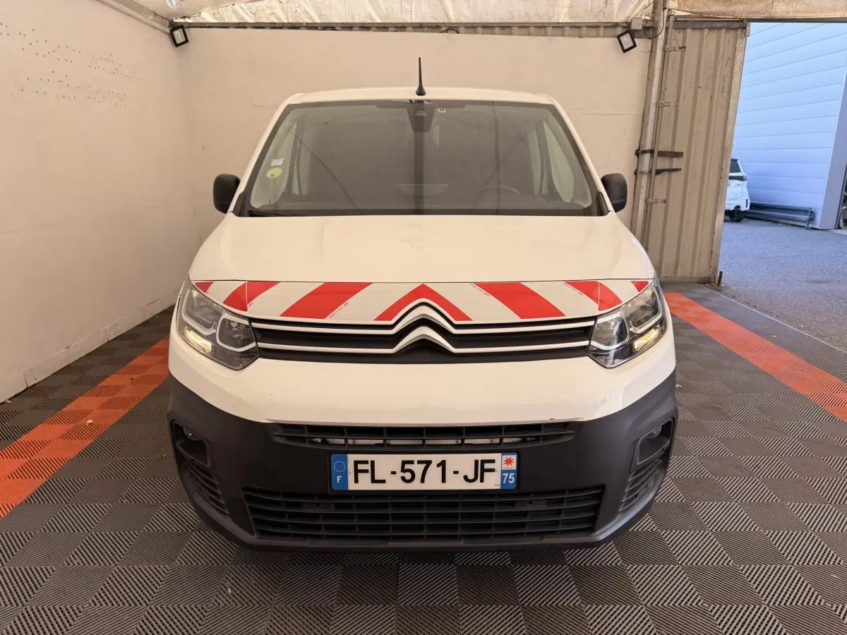 Vue de face d'un Citroën Berlingo blanc 2019 avec bande rouge et blanche sur le capot, dans un garage.
