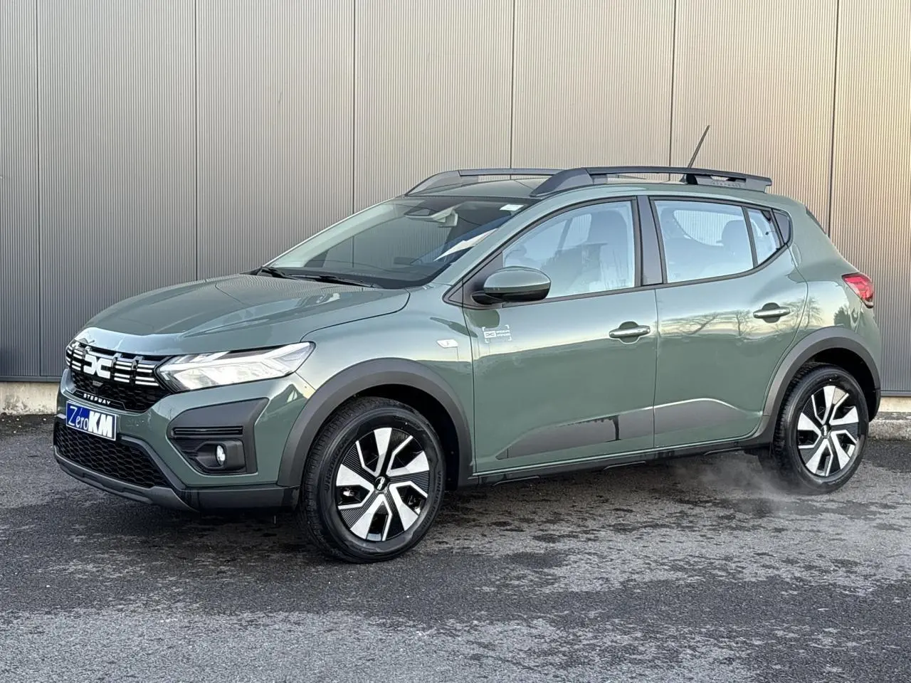 Dacia Sandero Stepway 2025 kaki lichen en 3/4 avant droit avec barres de toit et jantes spécifiques.