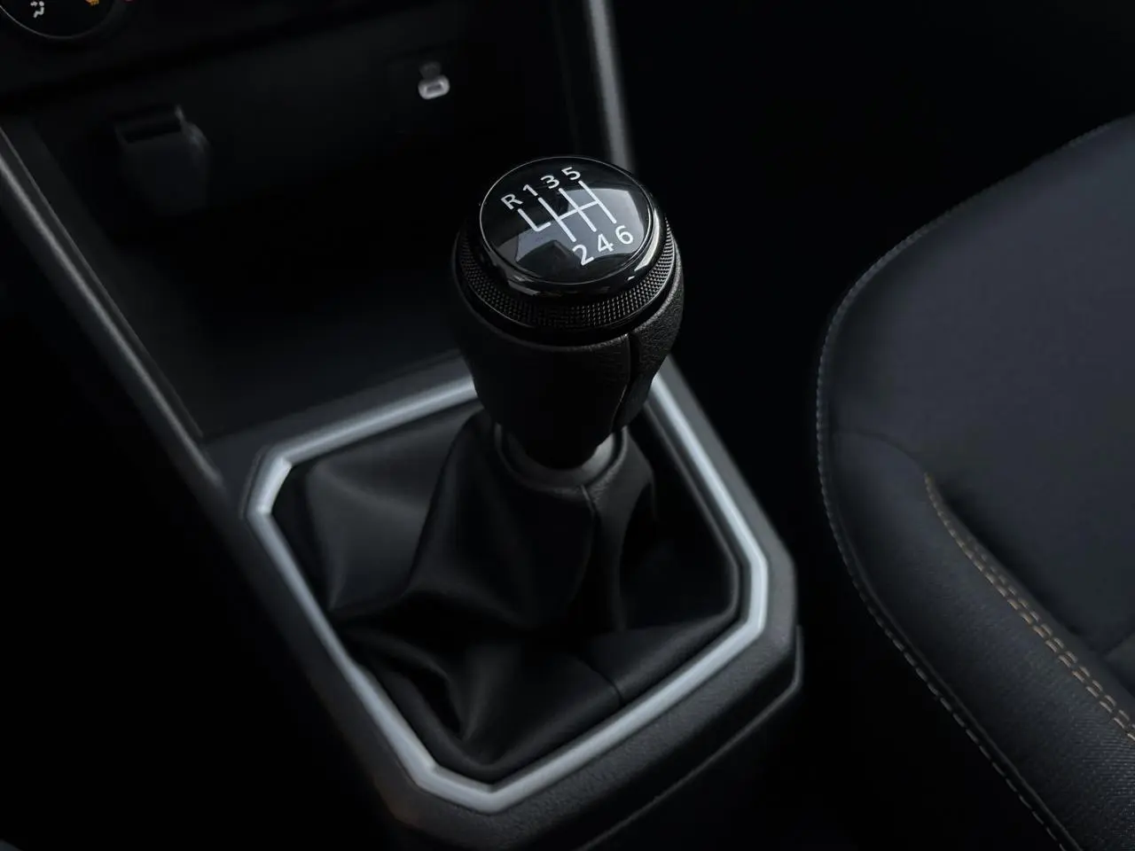 Gros plan sur le levier de vitesses manuel noir de la Dacia Sandero Stepway 2025, avec coutures marron du siège adjacent.