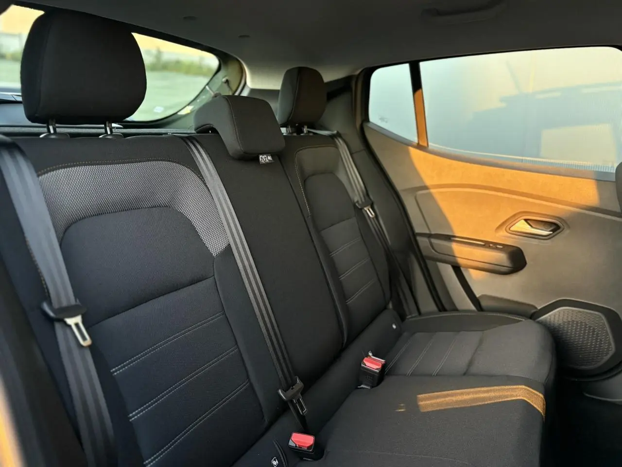 Vue latérale intérieure de la banquette arrière noire du Dacia Sandero Stepway 2025 avec ceintures et appuie-têtes.