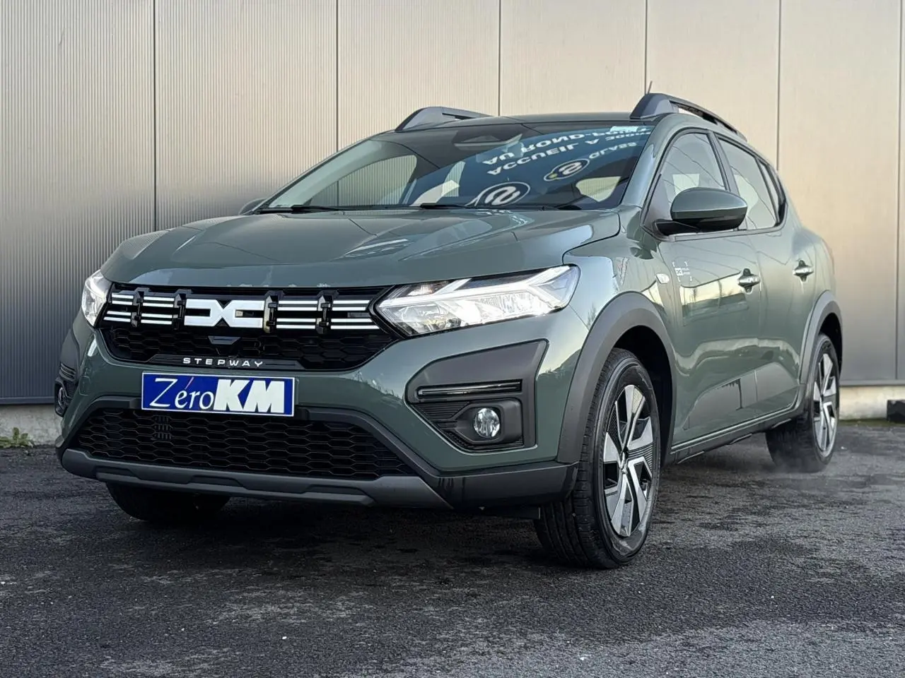 Dacia Sandero Stepway 2025 kaki lichen en 3/4 avant droit avec barres de toit et jantes spécifiques.