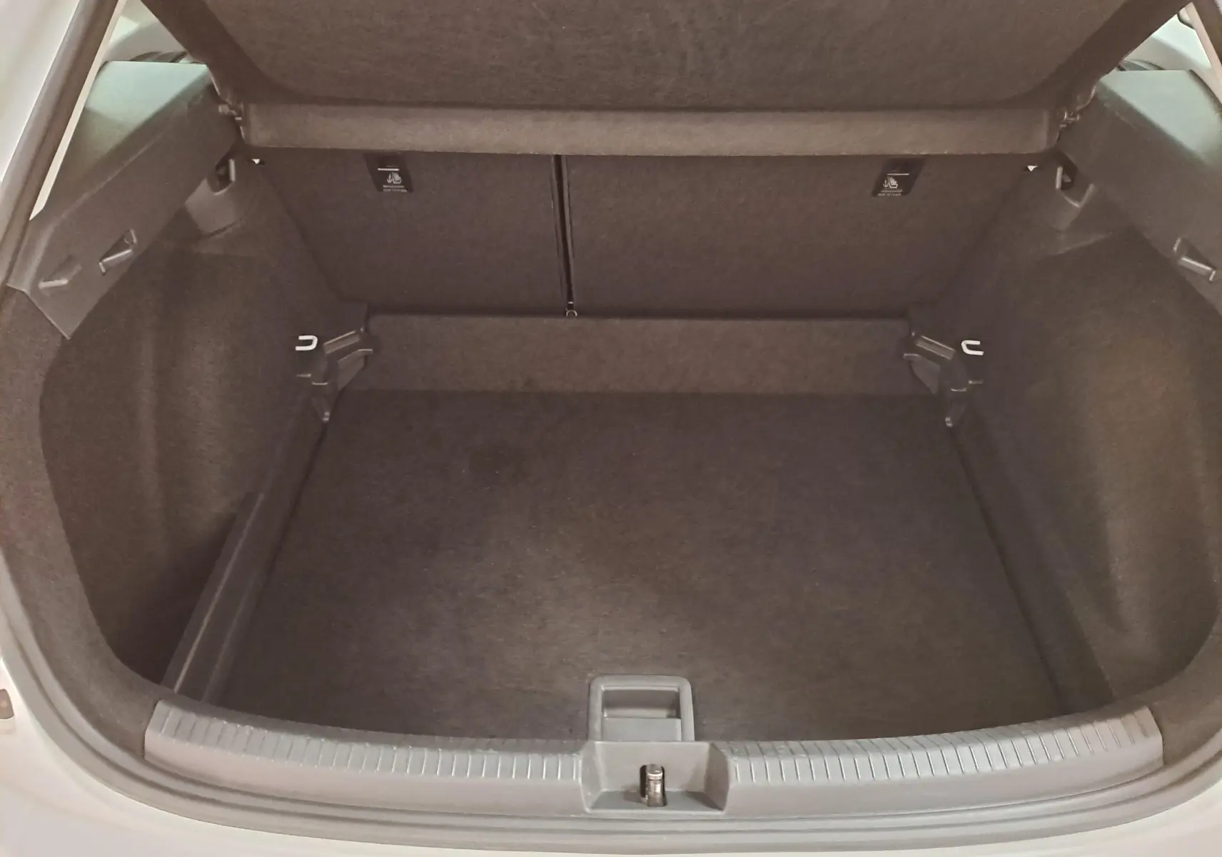 Coffre ouvert vu de l'arrière du Volkswagen Taigo blanc pur 2024, espace de chargement vide et propre.