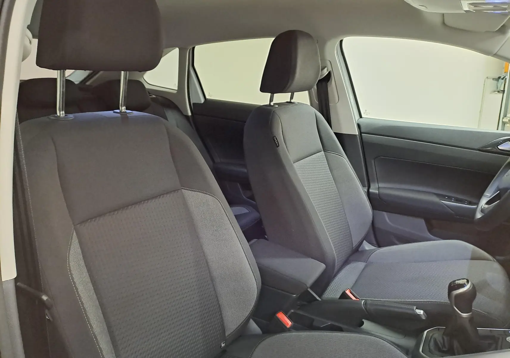 Vue intérieure côté droit du Volkswagen Taigo 2024, montrant les sièges avant en tissu gris et la boîte manuelle.