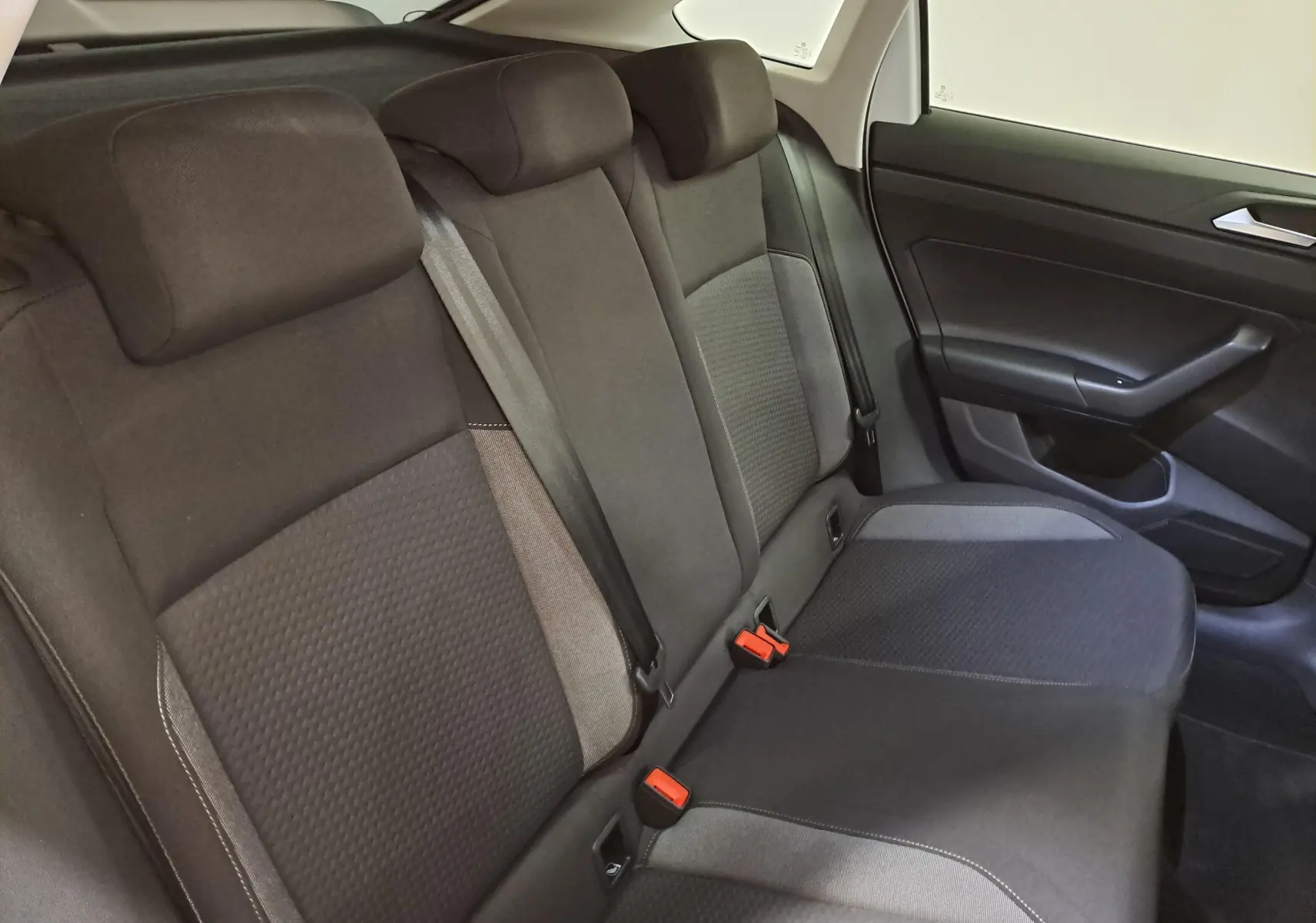 Vue intérieure côté droit des sièges arrière noirs et gris du Volkswagen Taigo 2024, avec ceintures et appuie-têtes visibles.