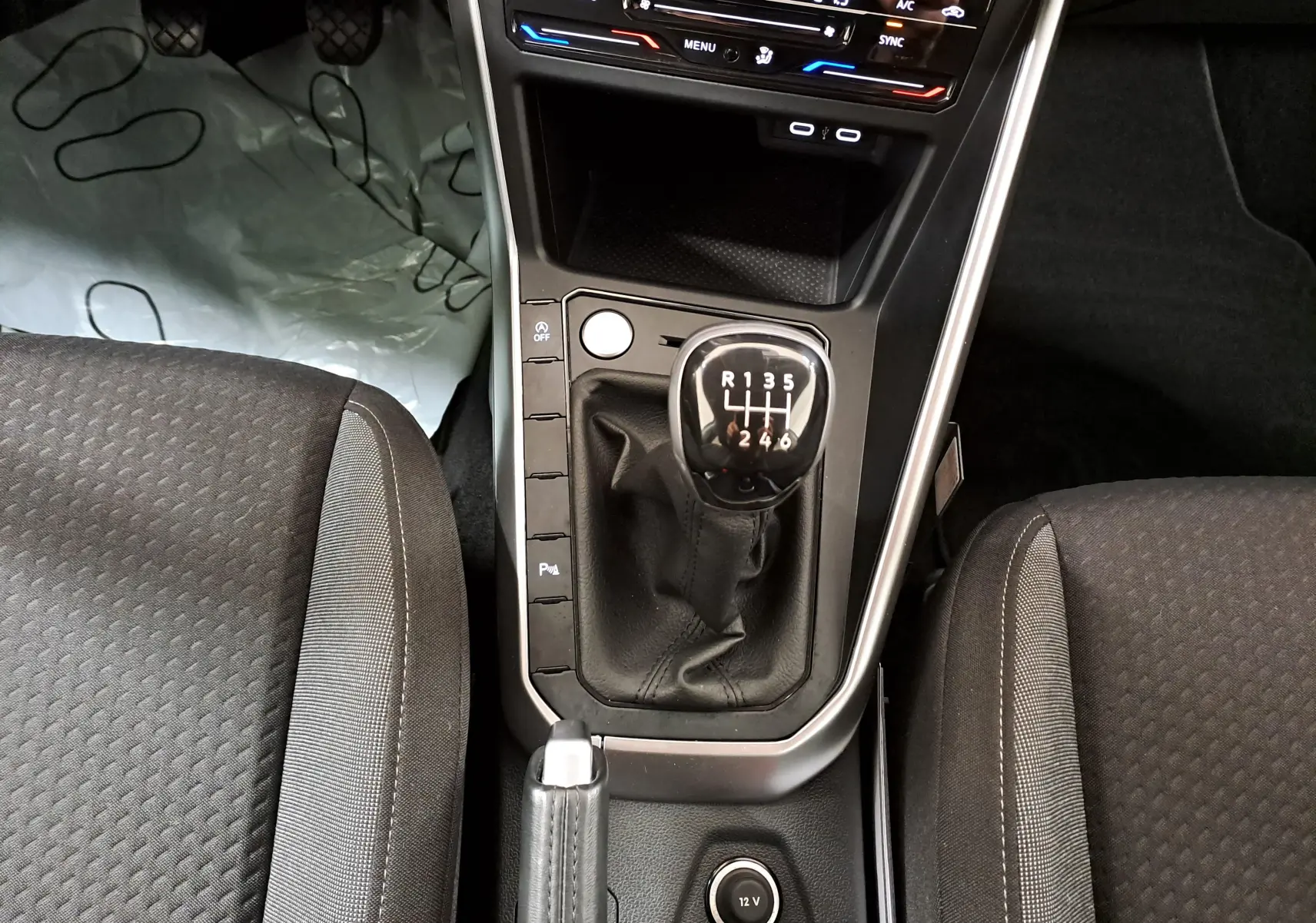 Vue plongeante sur la console centrale du Volkswagen Taigo 2024, avec levier de vitesse manuel et sièges tissu noirs.