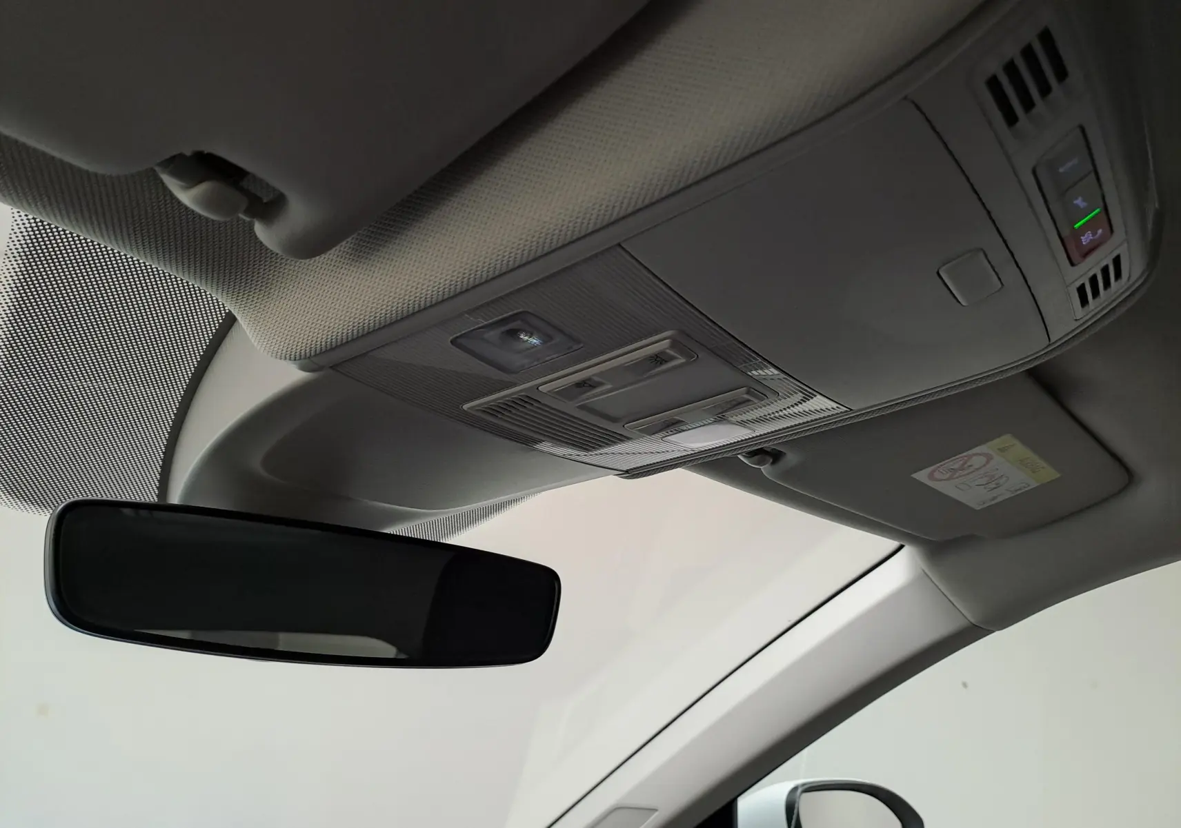 Vue intérieure du plafond avant du Volkswagen Taigo blanc, avec rétroviseur et commandes d'éclairage intégrées.