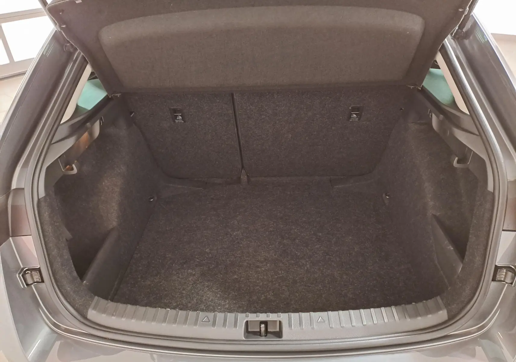 Coffre ouvert vu de l'arrière d'une Skoda Scala 2025 gris graphite, montrant l'espace de chargement vide.