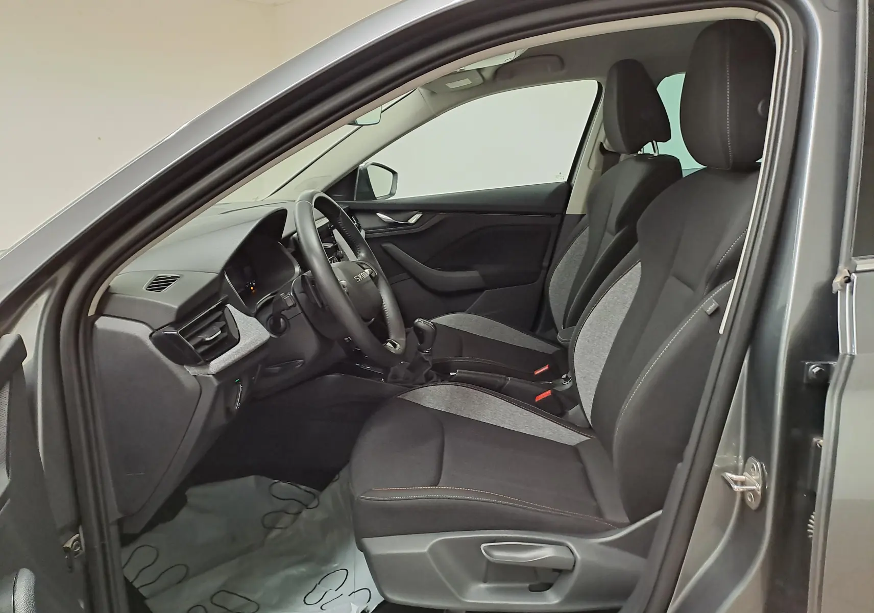 Intérieur côté conducteur d'une Skoda Scala 2025 gris graphite, sièges tissu bicolore et tableau de bord moderne.