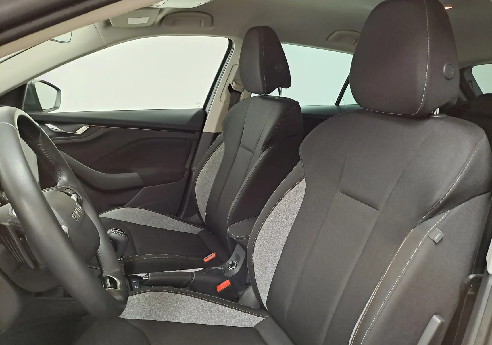 Vue intérieure côté gauche montrant les sièges avant en tissu noir et gris du Skoda Scala 2025.