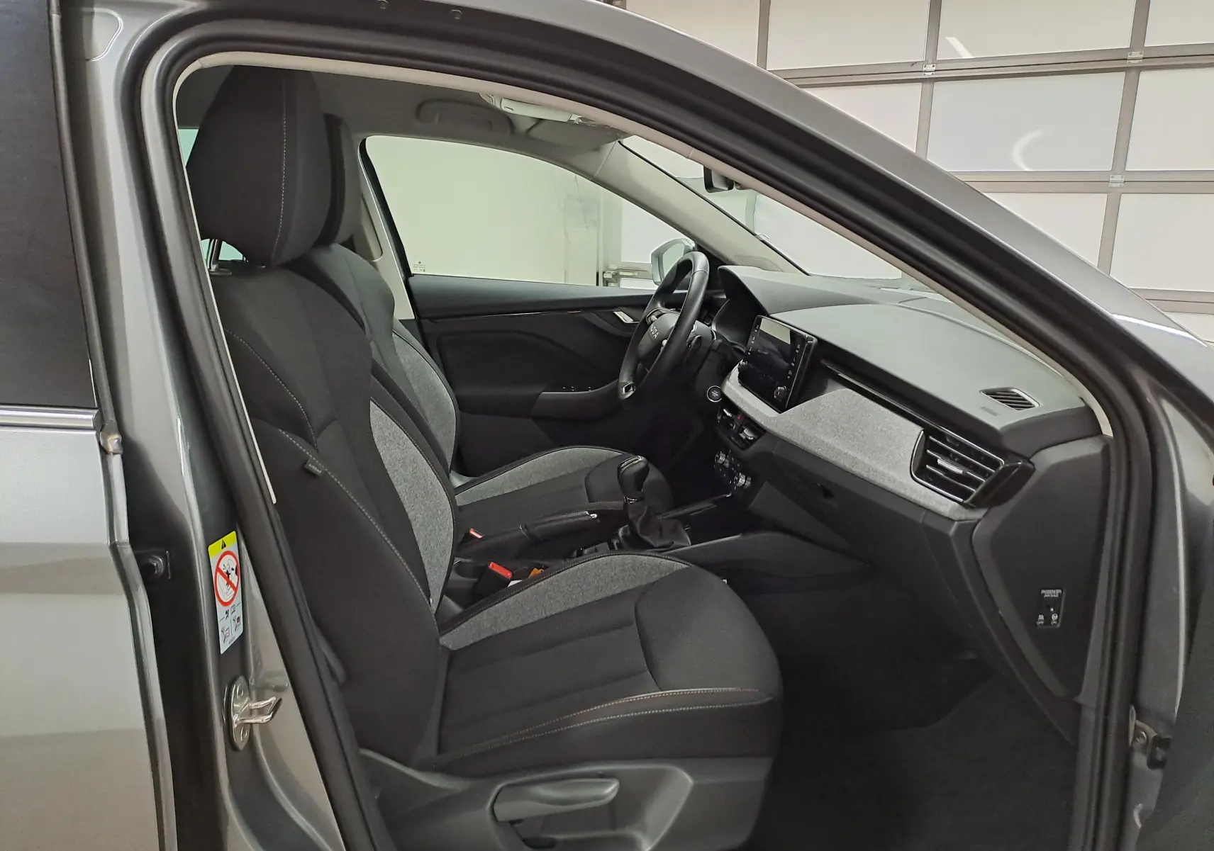 Vue intérieure côté conducteur de la Skoda Scala 2025 gris graphite, montrant sièges tissu bicolore et tableau de bord moderne.