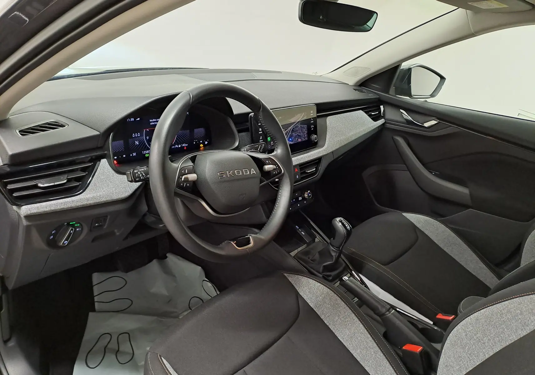 Vue intérieure côté conducteur du Skoda Scala 2025, montrant le volant, tableau de bord numérique et sellerie bicolore noire et grise.