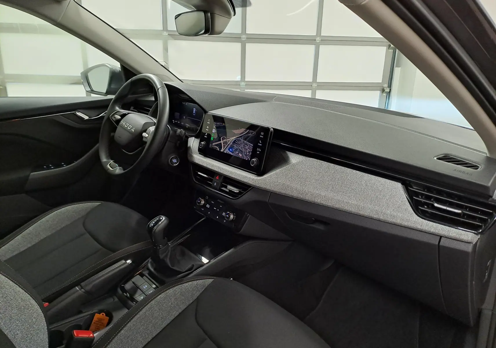 Vue intérieure côté conducteur de la Skoda Scala 2025 avec tableau de bord gris et écran tactile central affichant la caméra de recul.