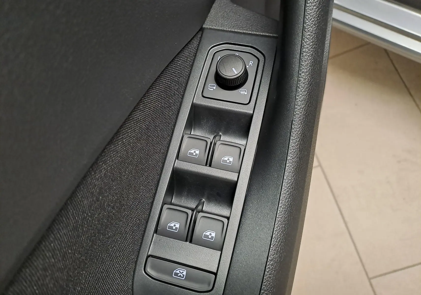 Vue rapprochée des commandes de lève-vitres et réglage des rétroviseurs sur la porte côté conducteur du Skoda Scala gris graphite.