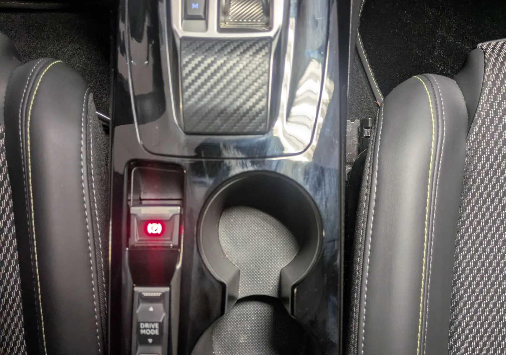 Vue plongeante sur la console centrale noire brillante du Peugeot 2008 Hybrid 145 GT avec levier de vitesses et porte-gobelets.