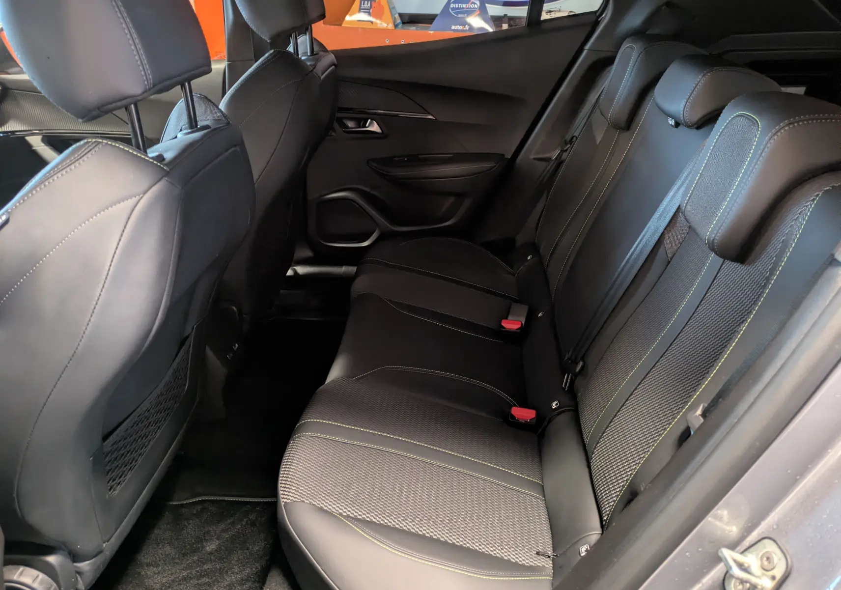 Vue intérieure côté droit des sièges arrière noirs avec surpiqûres vertes du Peugeot 2008 Hybrid 145 e-DCS6 GT 2025.