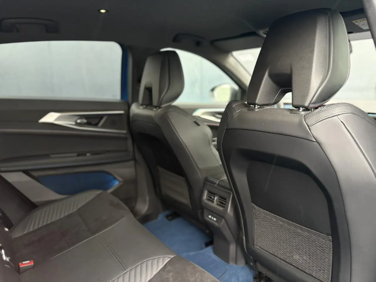 Vue intérieure arrière droite du Renault Rafale 4X4 E-Tech bleu sommet, avec sellerie noire et inserts bleus raffinés.