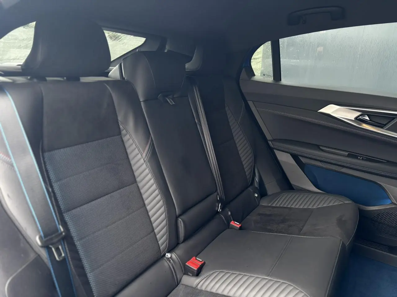 Vue intérieure arrière côté droit du Renault Rafale 2025, sièges en Alcantara noir avec surpiqûres bleues et inserts textiles.