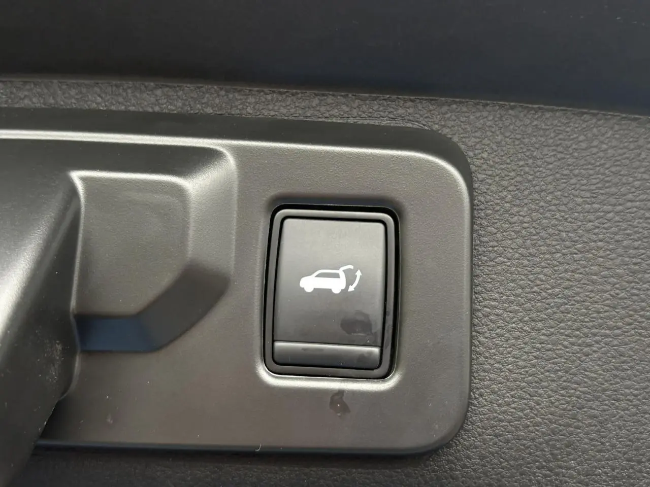 Bouton intérieur noir pour ouverture motorisée du hayon sur Renault Rafale 4x4 E-Tech bleu sommet, vue rapprochée.