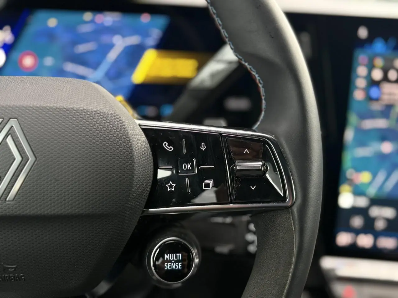 Gros plan sur le volant noir avec commandes tactiles et bouton Multi-Sense du Renault Rafale 4x4 E-Tech.