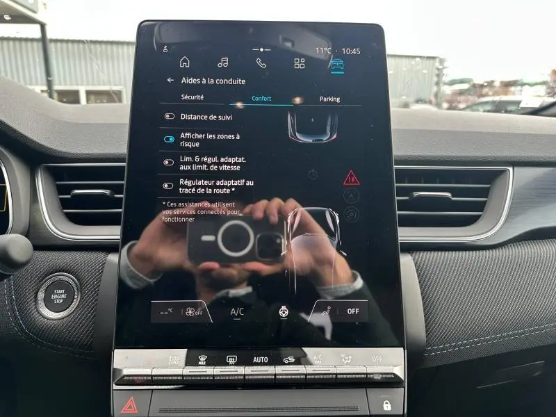 Écran tactile central du Renault Captur 2026 avec interface d’aides à la conduite, tableau de bord gris et bouton start/stop visible.