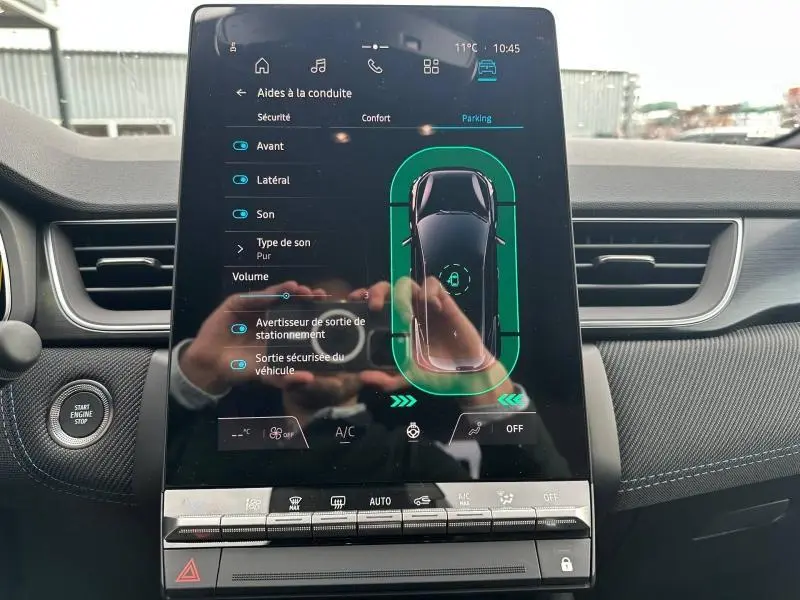 Écran tactile central du Renault Captur 2026 affichant l'aide au stationnement avec vue du véhicule noir sur fond vert.