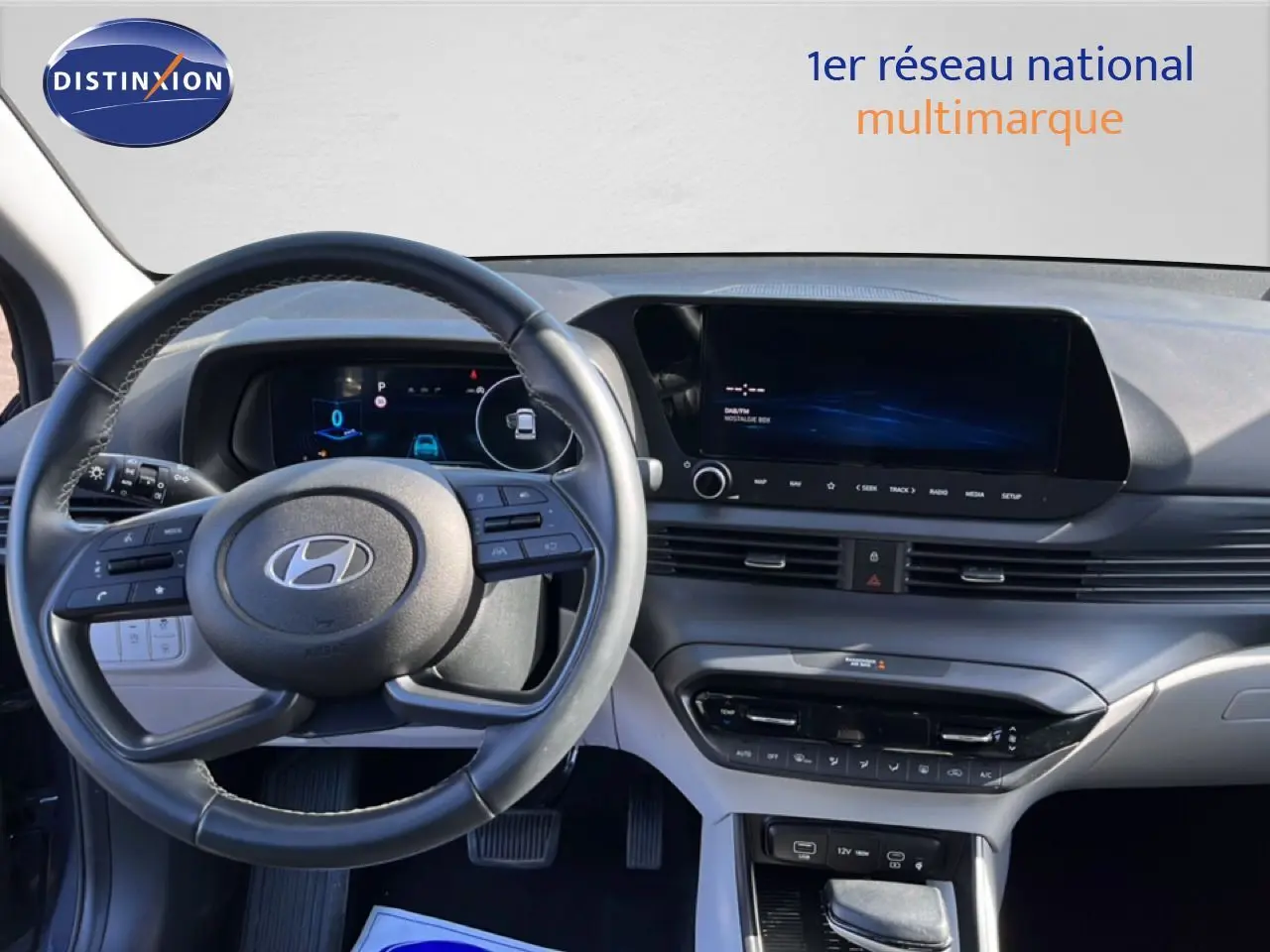 Vue intérieure du tableau de bord et volant de la Hyundai i20 2025 gris Aurora Metal avec écran tactile et commandes au volant.