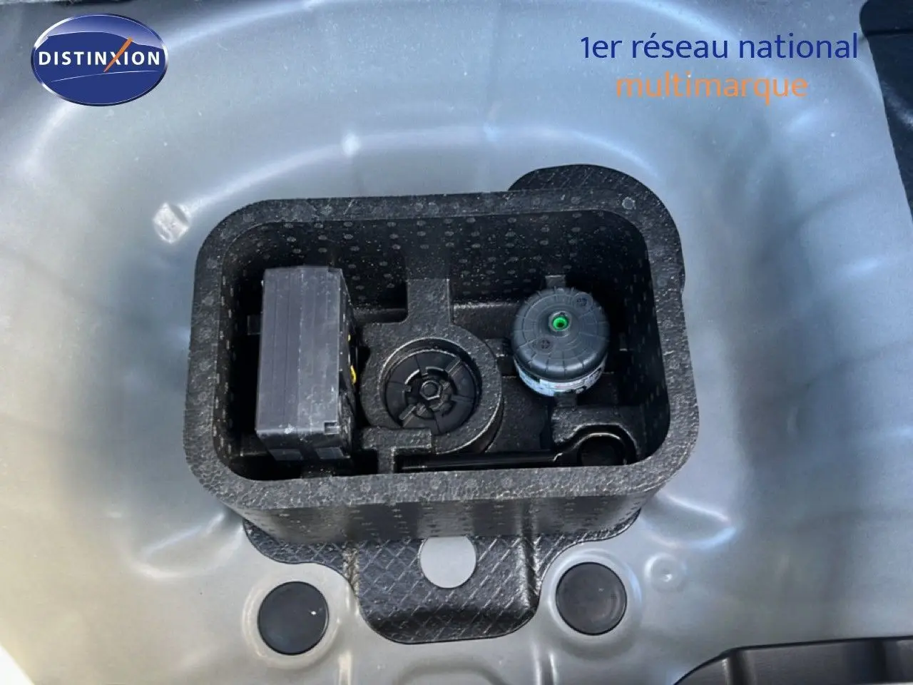 Vue plongeante sur le coffre d’une Hyundai i20 gris Aurora Metal montrant le rangement pour outils et compresseur.