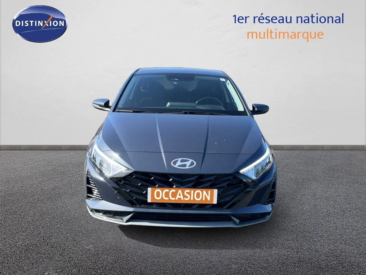 Vue avant d'une Hyundai i20 1.0 T-GDI gris Aurora Metal avec calandre noire et phares LED allumés.