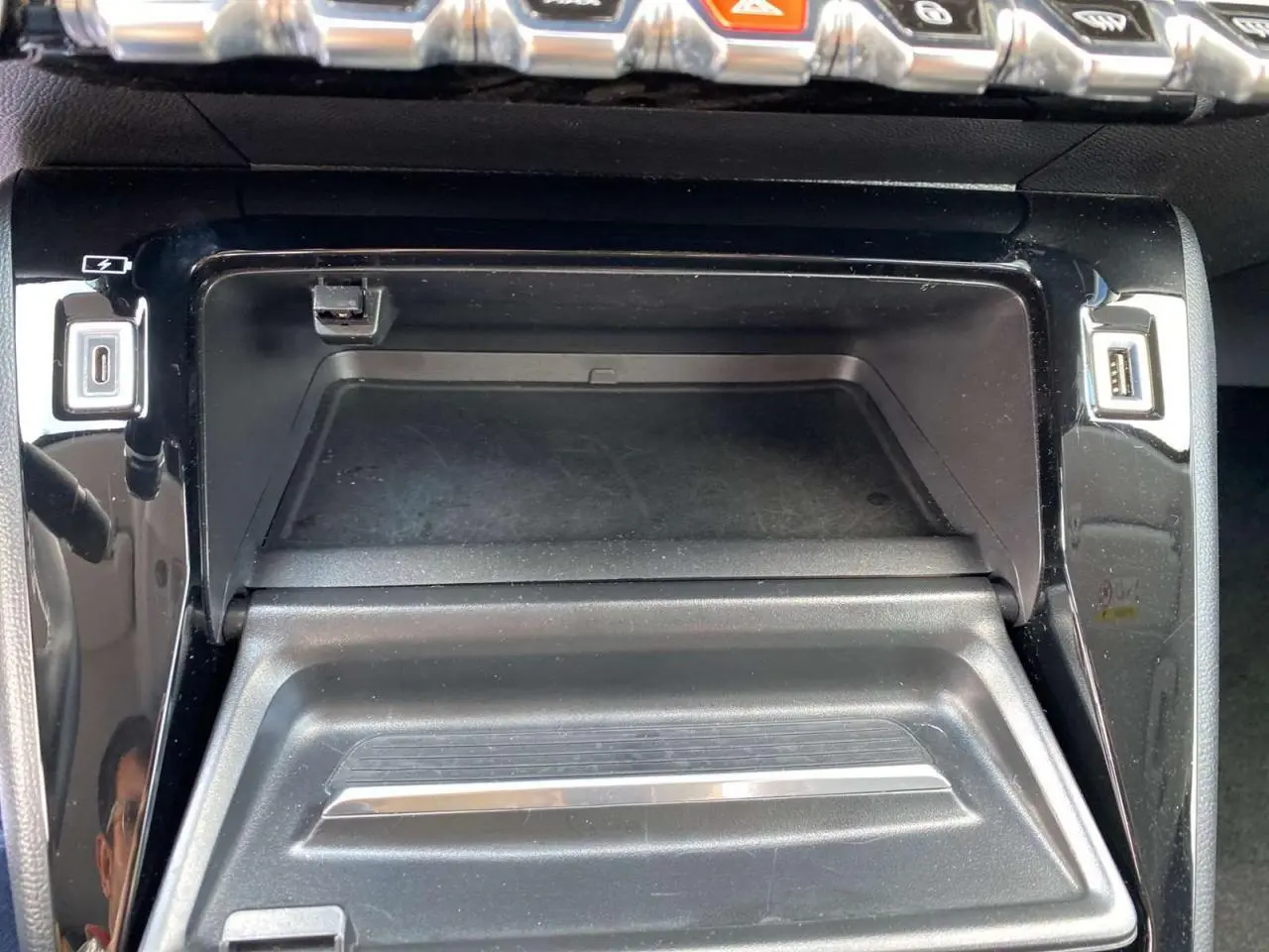 Vue rapprochée du compartiment central avec prises USB et finition noire brillante dans une Peugeot 208 2021.