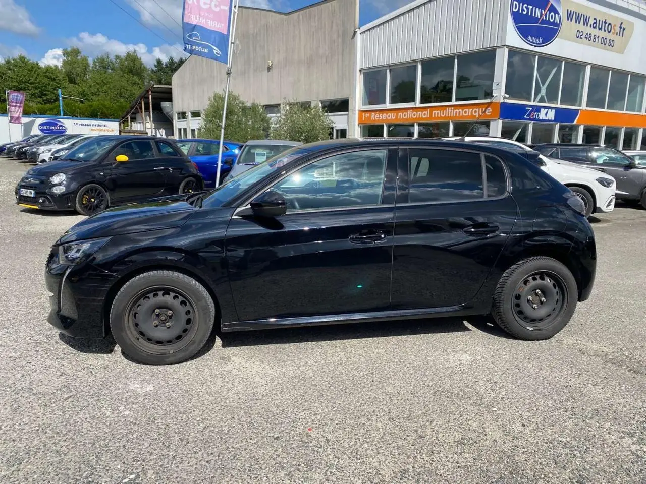 Peugeot 208 noire vue de profil côté gauche, avec jantes acier et carrosserie brillante, stationnée en extérieur.