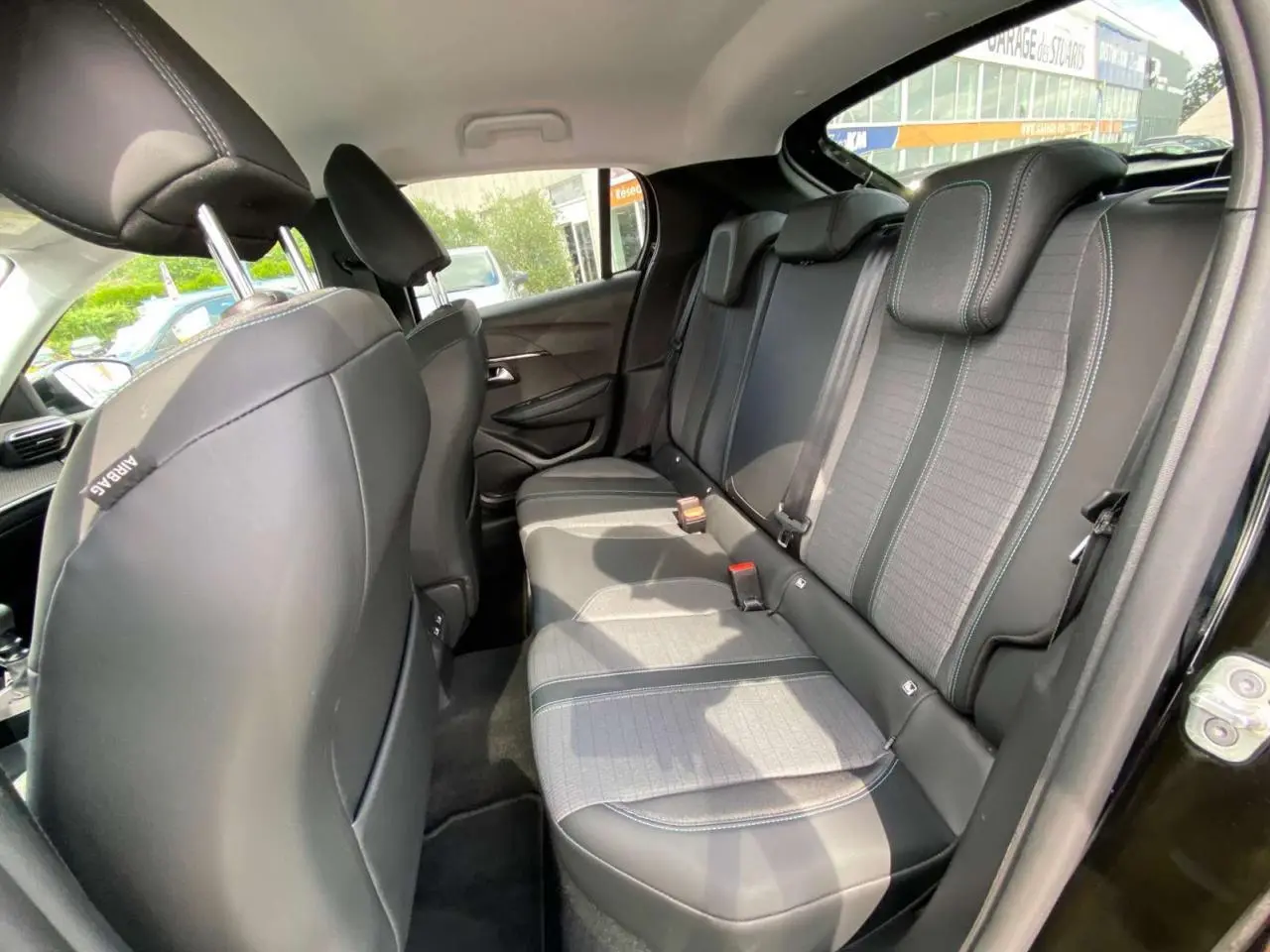 Vue intérieure côté droit des sièges arrière noirs avec surpiqûres blanches d'une Peugeot 208 noire de 2021.
