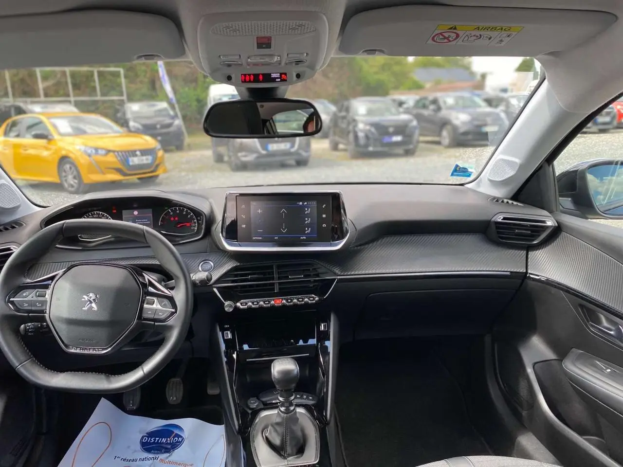Vue intérieure avant de la Peugeot 208 noire 2021, tableau de bord moderne avec écran tactile et volant compact.