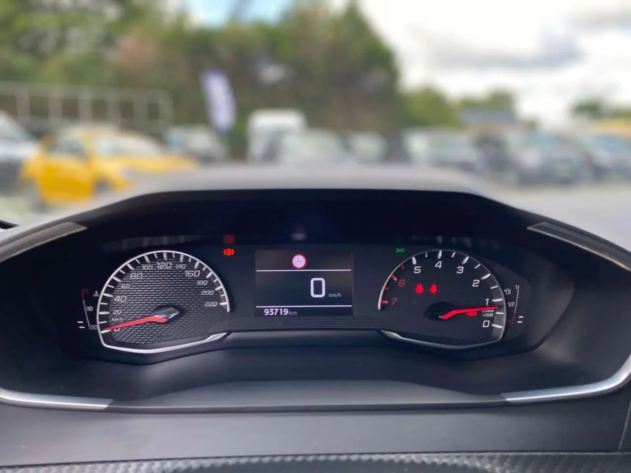 Vue rapprochée du tableau de bord numérique de la Peugeot 208 noire, affichant compteur et compte-tours.