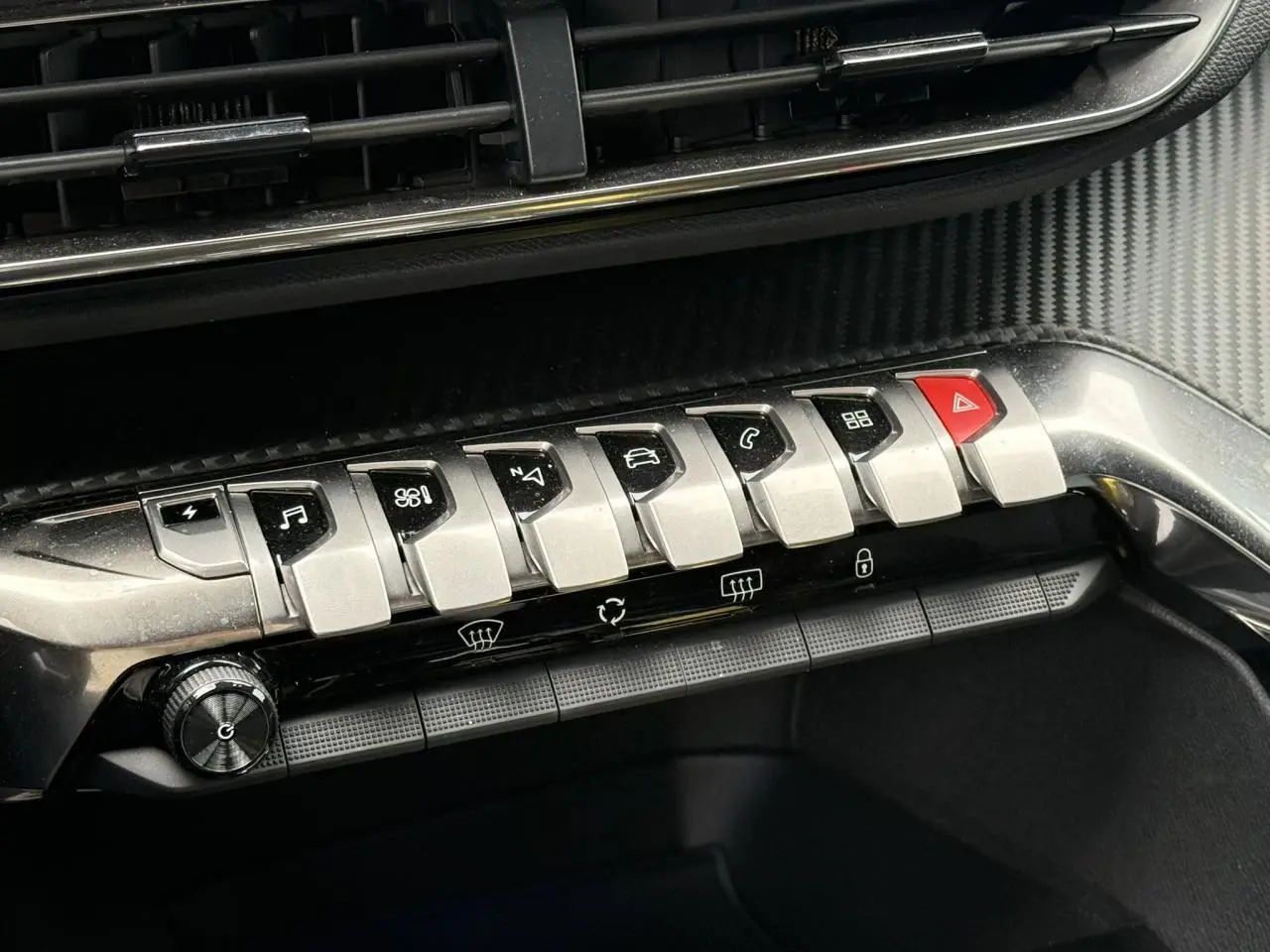 Gros plan sur la rangée de boutons argentés et noirs du tableau de bord du Peugeot 3008 Plug-in Hybrid gris Artense.