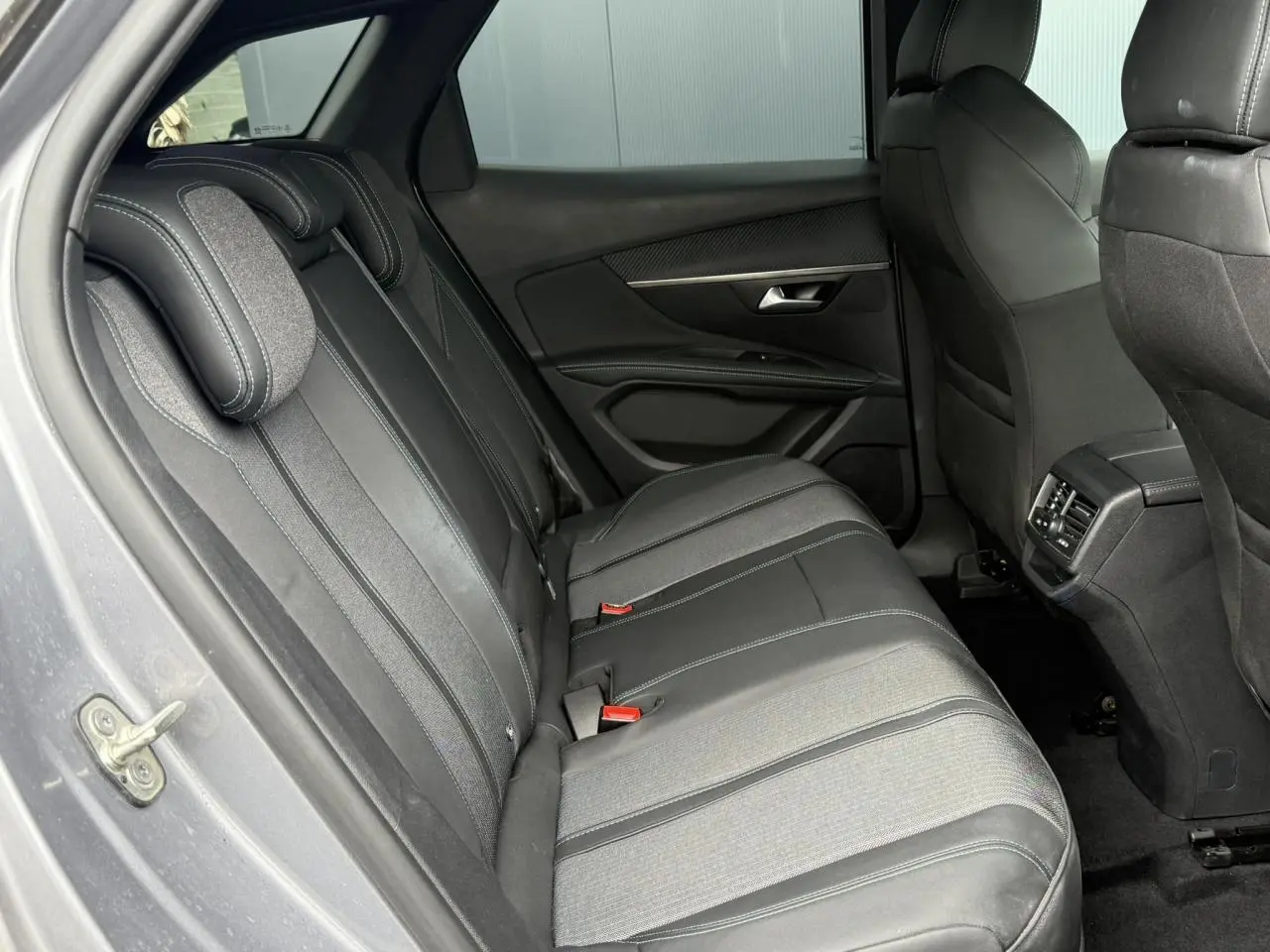 Vue intérieure arrière côté gauche du Peugeot 3008 2024 gris Artense, sièges en cuir et tissu noir avec surpiqûres contrastées.