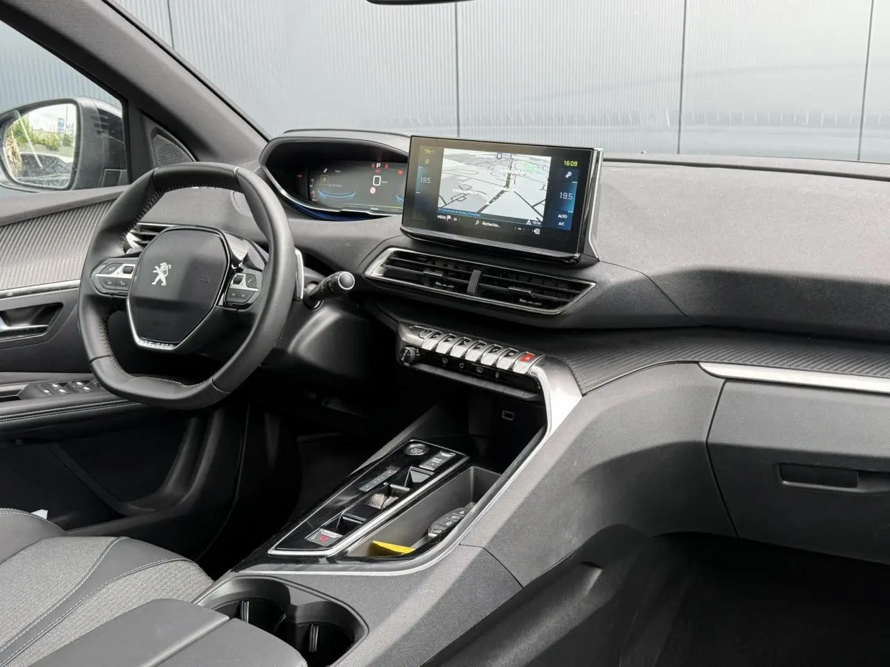 Vue intérieure côté conducteur du Peugeot 3008 Plug-in Hybrid 2024, tableau de bord noir avec écran tactile central et volant compact.