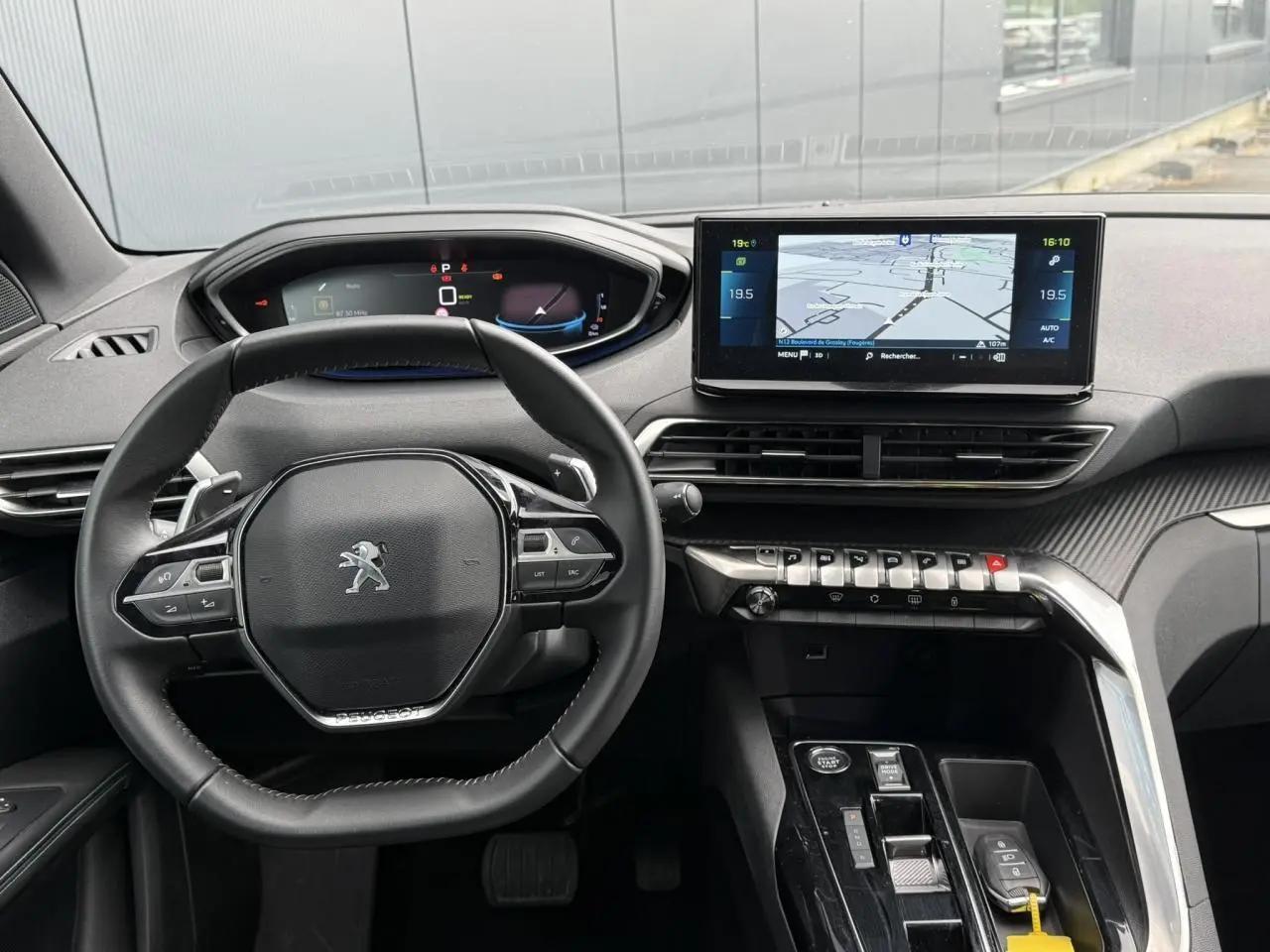 Vue intérieure frontale du tableau de bord du Peugeot 3008 Plug-in Hybrid 2024 avec volant compact et écran tactile de navigation.