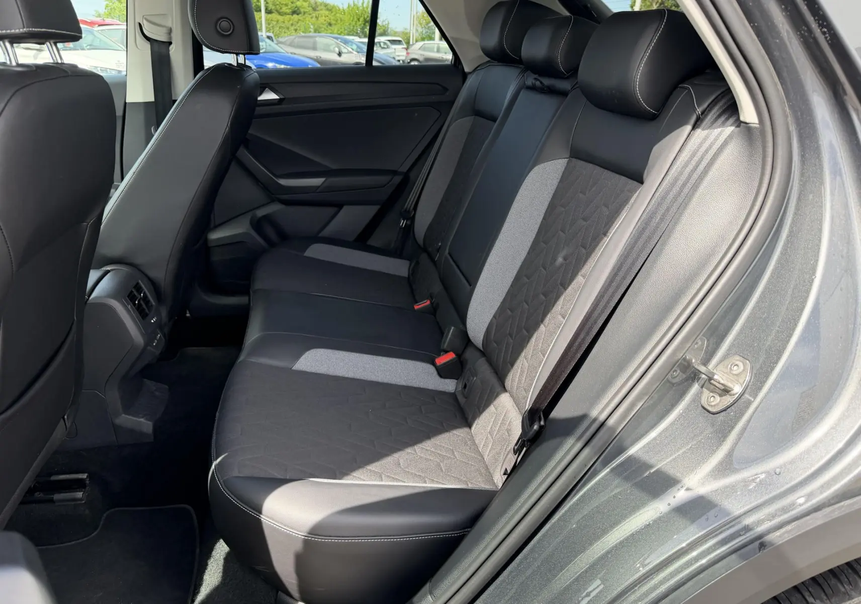 Vue côté droit de l'intérieur arrière du Volkswagen T-Roc gris 2025, avec sièges bicolores en tissu et cuir.