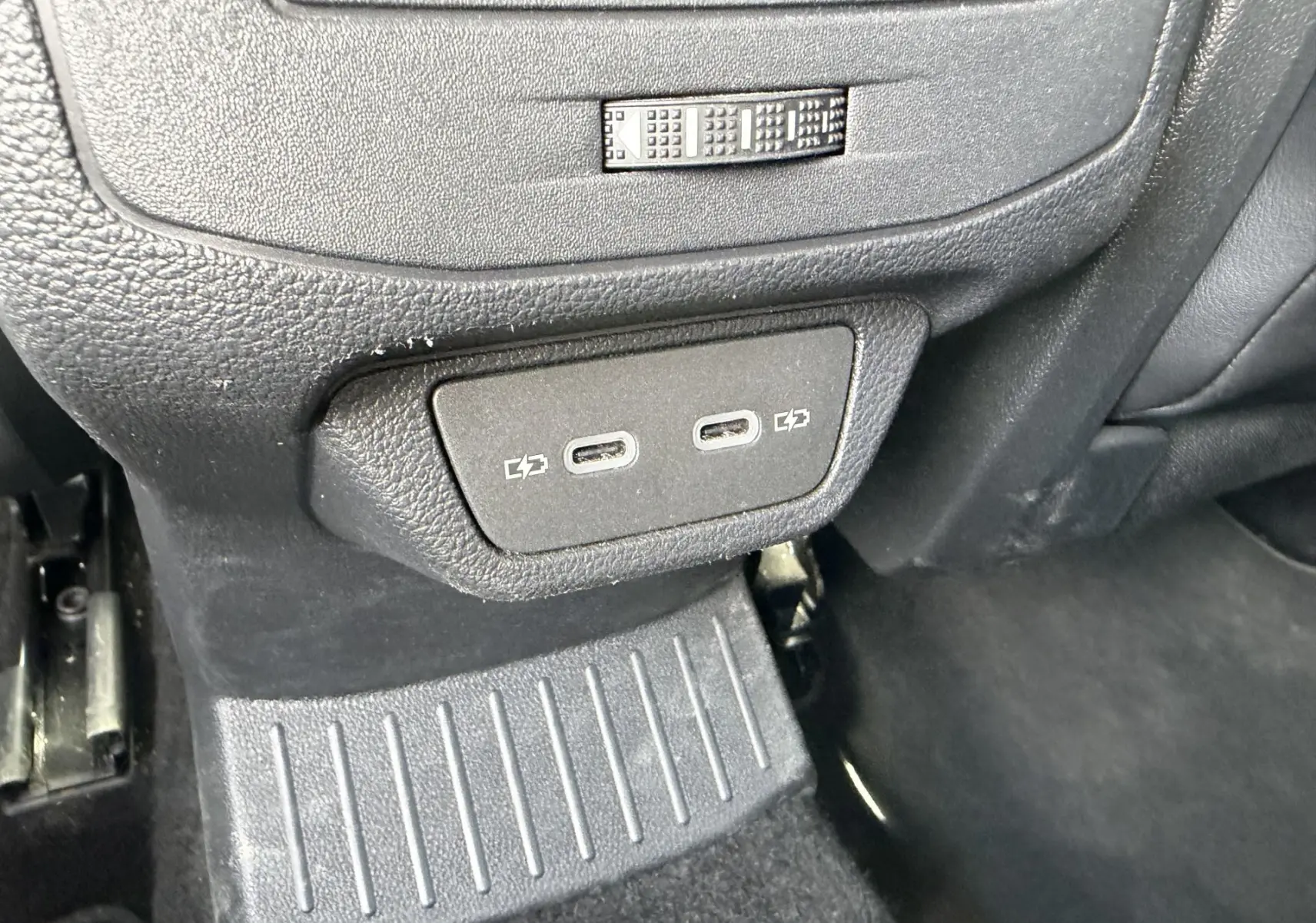 Gros plan sur les ports USB-C de recharge situés à l'arrière de la console centrale d'un Volkswagen T-Roc gris.