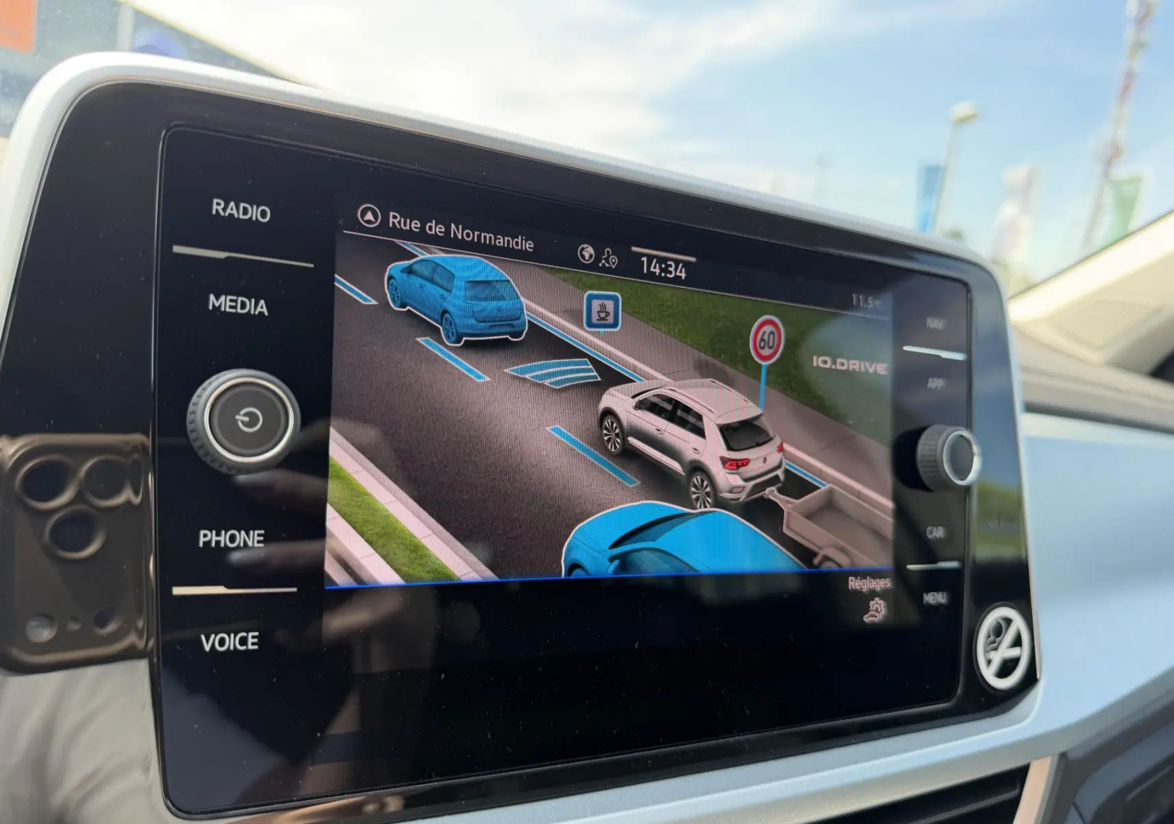 Écran central du Volkswagen T-Roc montrant l'assistance au stationnement avec vue 3D des véhicules environnants.