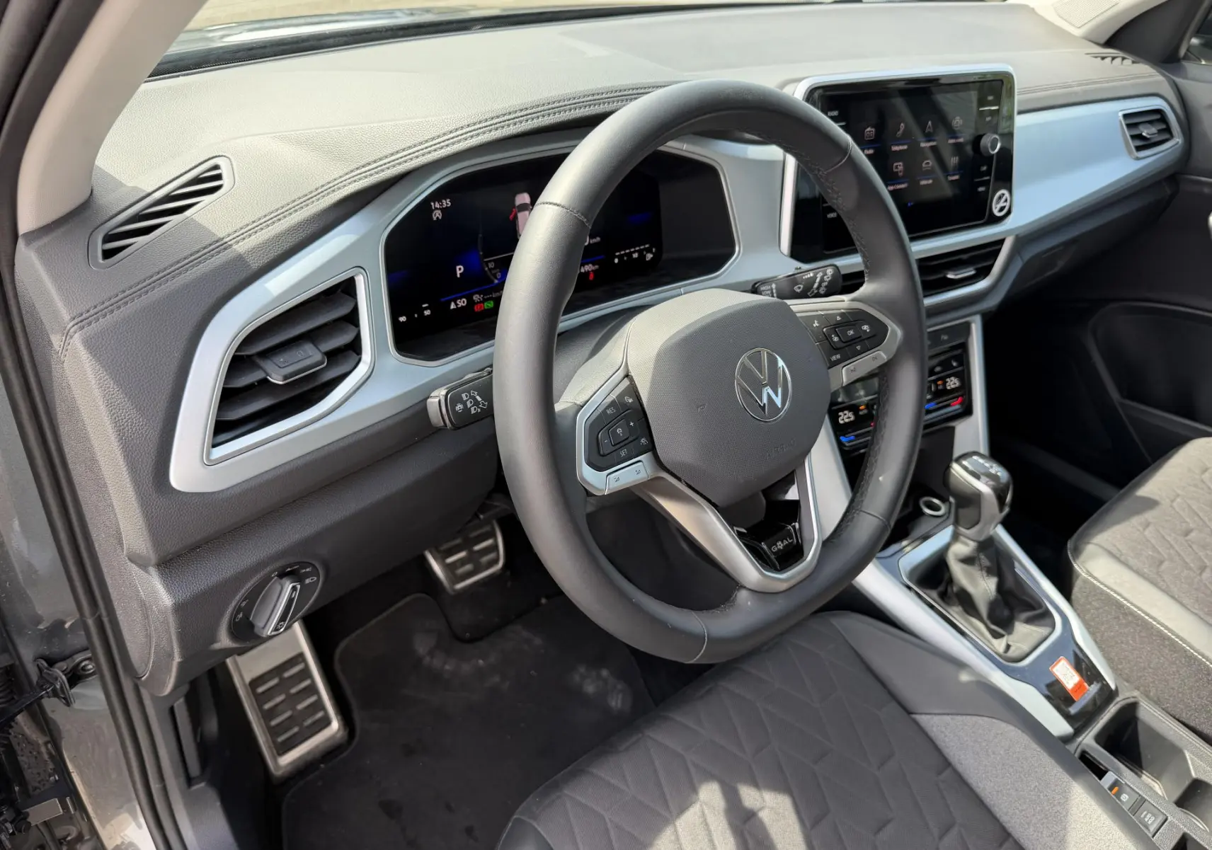 Vue intérieure côté conducteur du Volkswagen T-Roc gris 2025, volant cuir multifonction et tableau de bord digital.