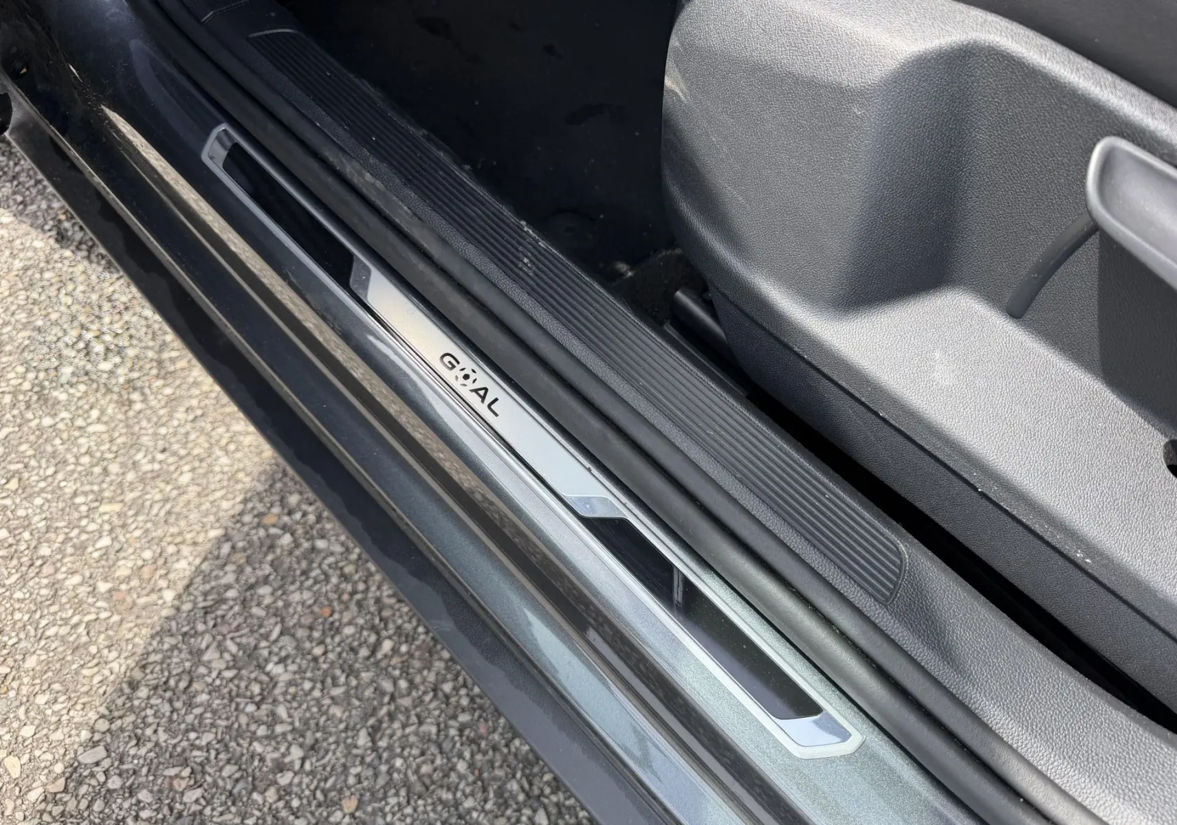 Gros plan sur la plaque de seuil de porte côté gauche du Volkswagen T-Roc gris, avec intérieur en plastique noir.