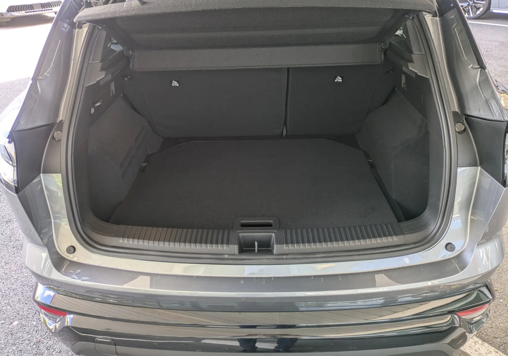 Coffre ouvert vu de l'arrière du Renault Austral E-Tech 200 gris schiste avec intérieur noir et seuil de chargement visible.