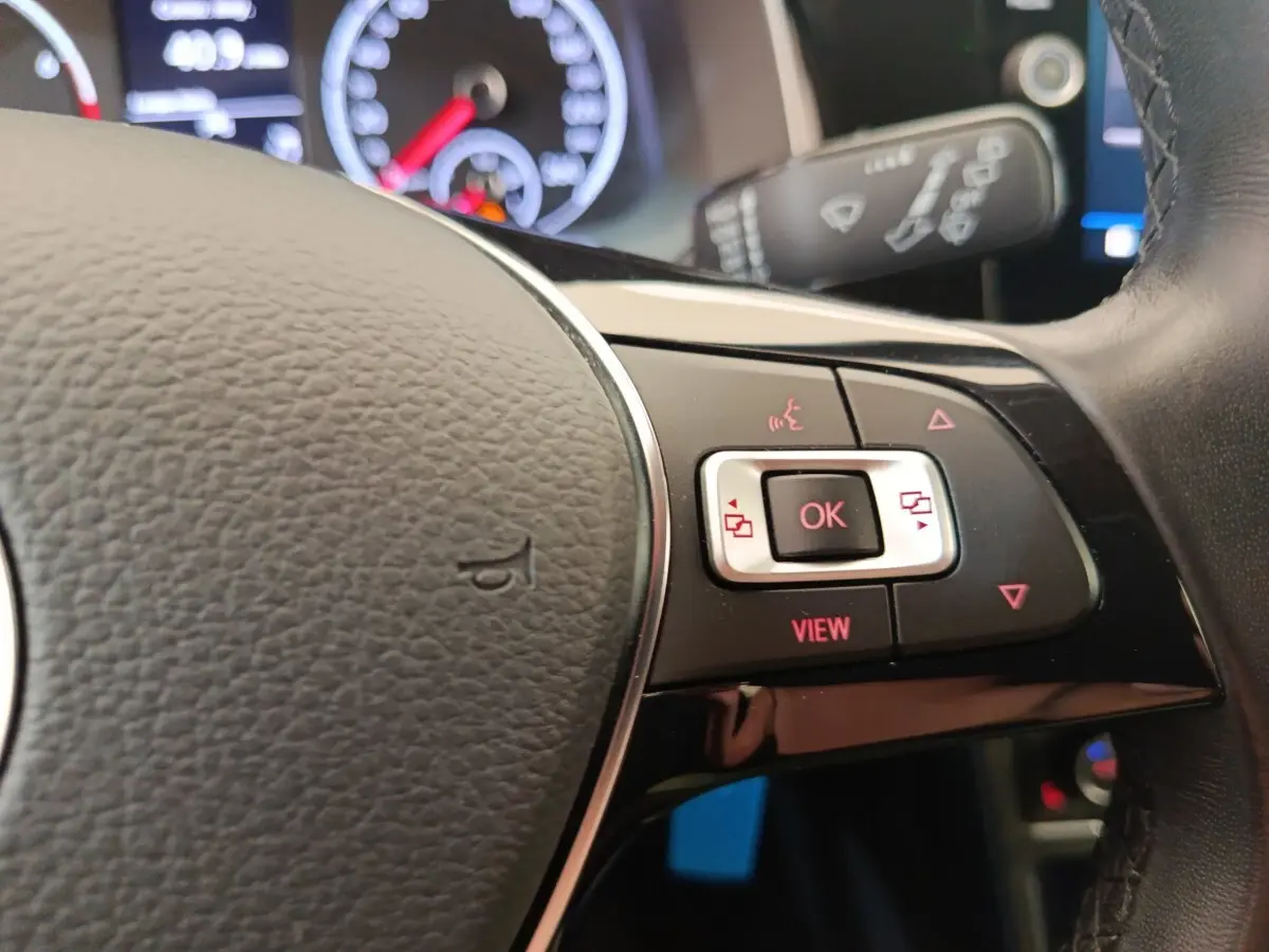 Gros plan sur le volant cuir et alu de la Volkswagen Polo 1.0 TSI 95 United avec commandes multifonctions rouges.