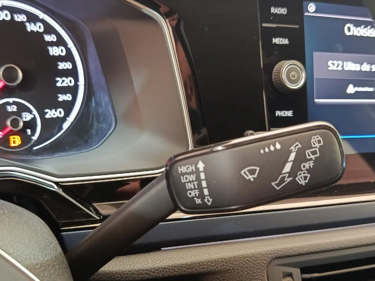 Gros plan intérieur sur le commodo d’essuie-glaces de la Volkswagen Polo 1.0 TSI 95 United, tableau de bord noir visible.
