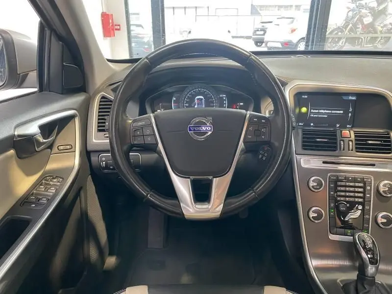 Vue intérieure centrée sur le volant cuir multifonction du Volvo XC60 argenté, avec tableau de bord et écran multimédia visible.