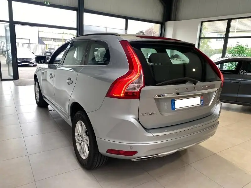 Volvo XC60 D4 argenté vu en 3/4 arrière droit, avec feux arrière LED et double sortie d’échappement chromée.