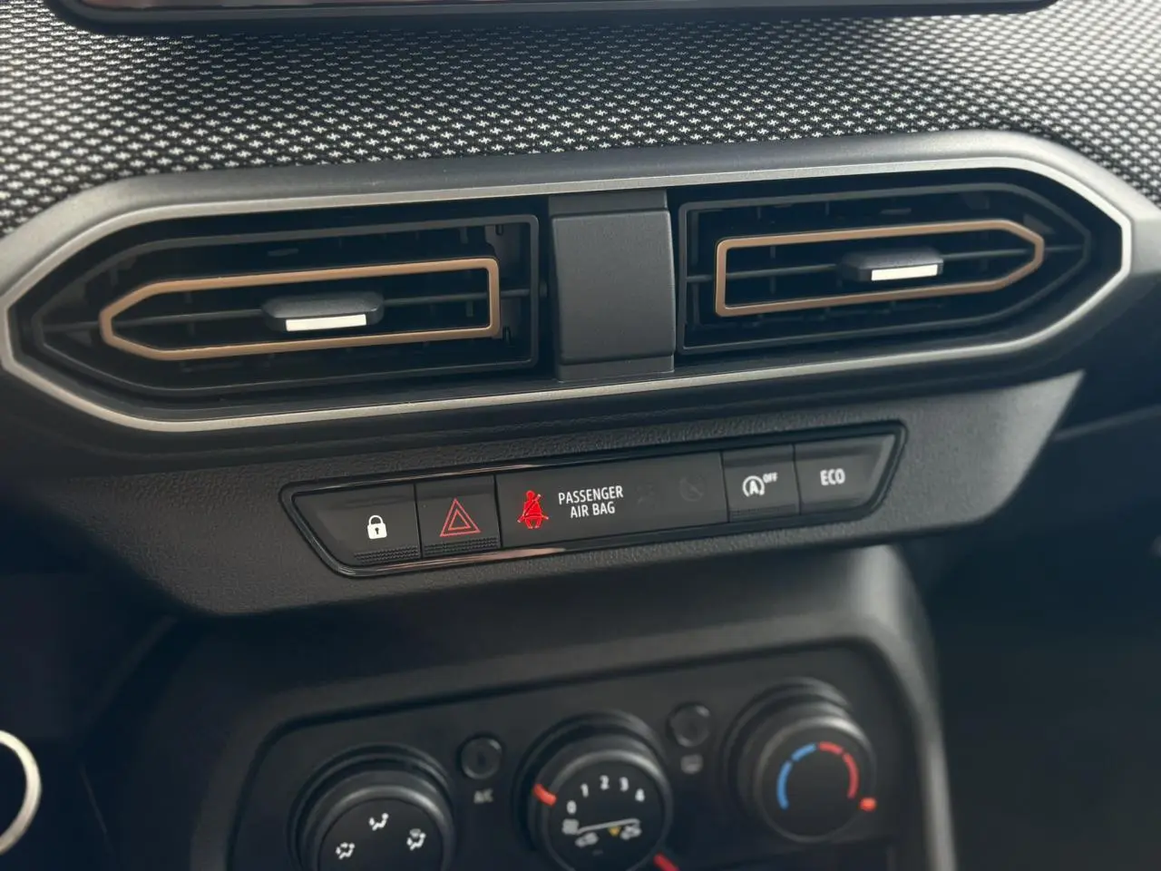 Détail du tableau de bord du Dacia Sandero Stepway 2025, avec aérateurs hexagonaux et commandes de climatisation noires.