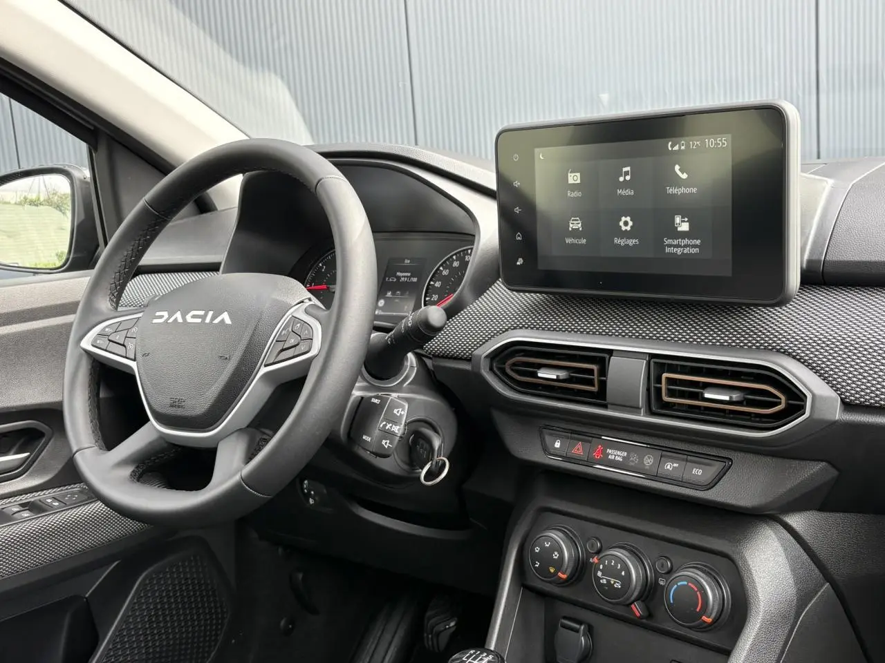 Vue intérieure côté conducteur du tableau de bord gris foncé de la Dacia Sandero Stepway 2025 avec écran tactile et volant marqué Dacia.